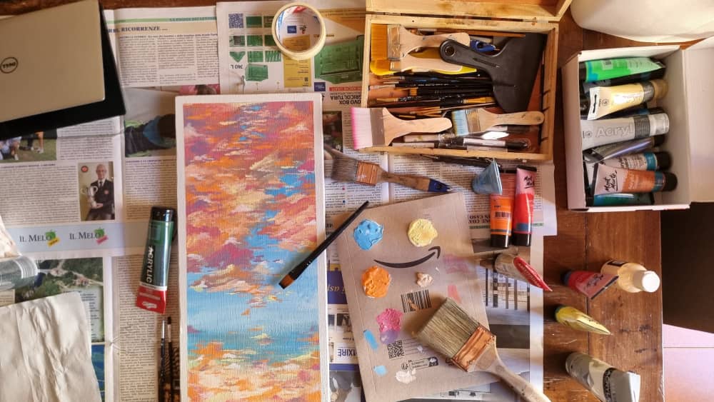 Art supplies and acrylic painting on a wooden table, showcasing collaboration with local crafters for custom artistry in interior design.