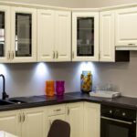 Modern kitchen with white cabinets, black countertop, and colorful decorative vases.