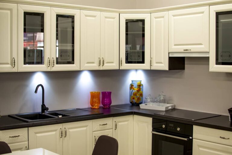 Modern kitchen with white cabinets, black countertop, and colorful decorative vases.