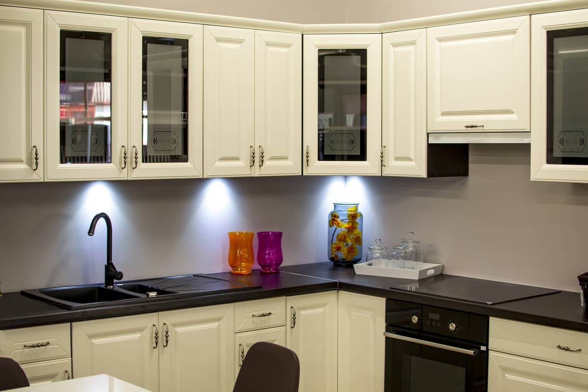 Modern kitchen with white cabinets, black countertop, and colorful decorative vases.